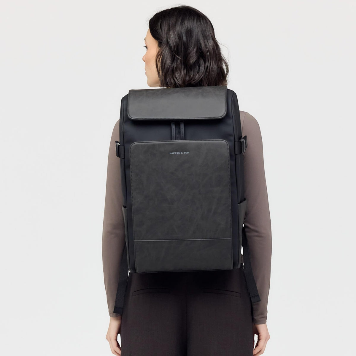 Lieblingstasche Bali Pro black backpack with faux leather front panel and adjustable straps, worn by a woman.