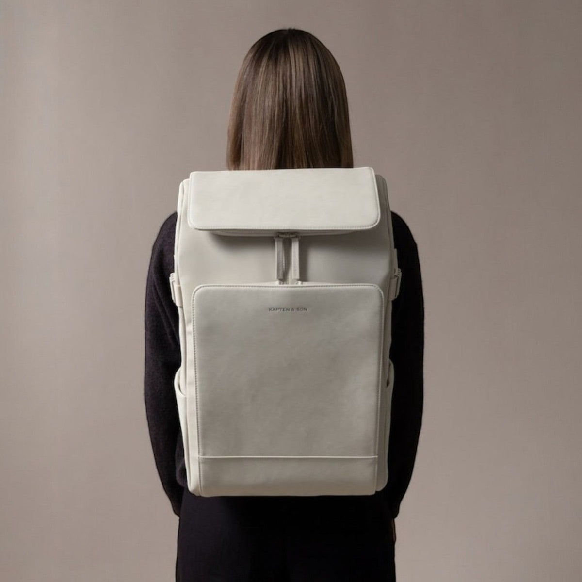 Lieblingstasche Bali Pro light grey vegan leather backpack with flap closure and front pocket, worn by a person.