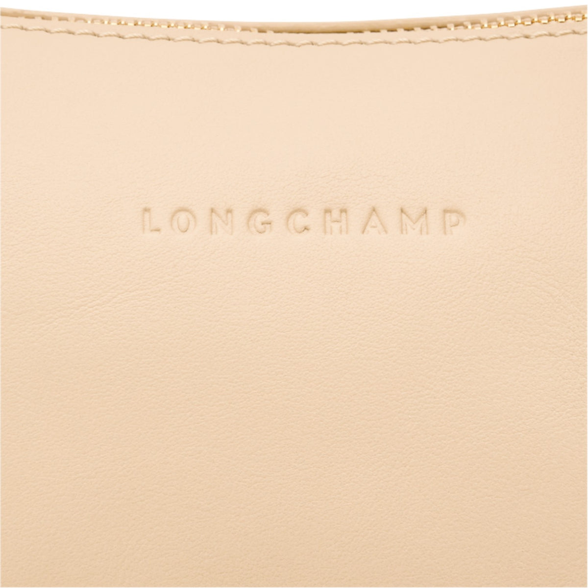 Close-up of a beige leather Lieblingstasche shoulder bag featuring the embossed Longchamp logo and gold zipper detail.
