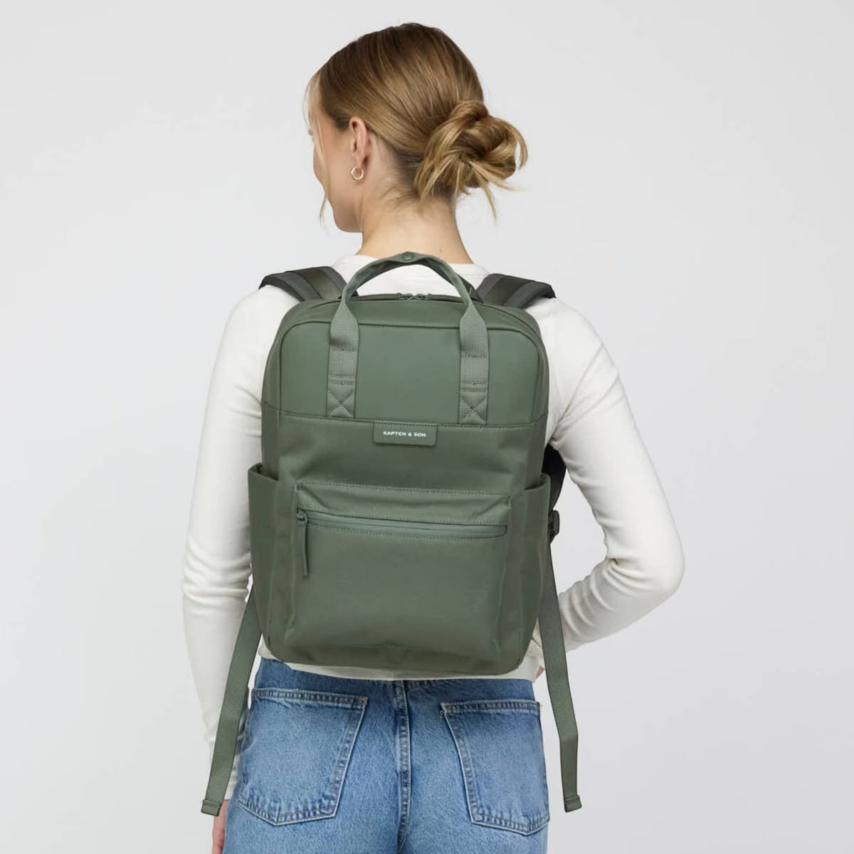 Lieblingstasche Bergen Pro backpack in olive green, worn on the back by a woman in a white long-sleeve shirt.