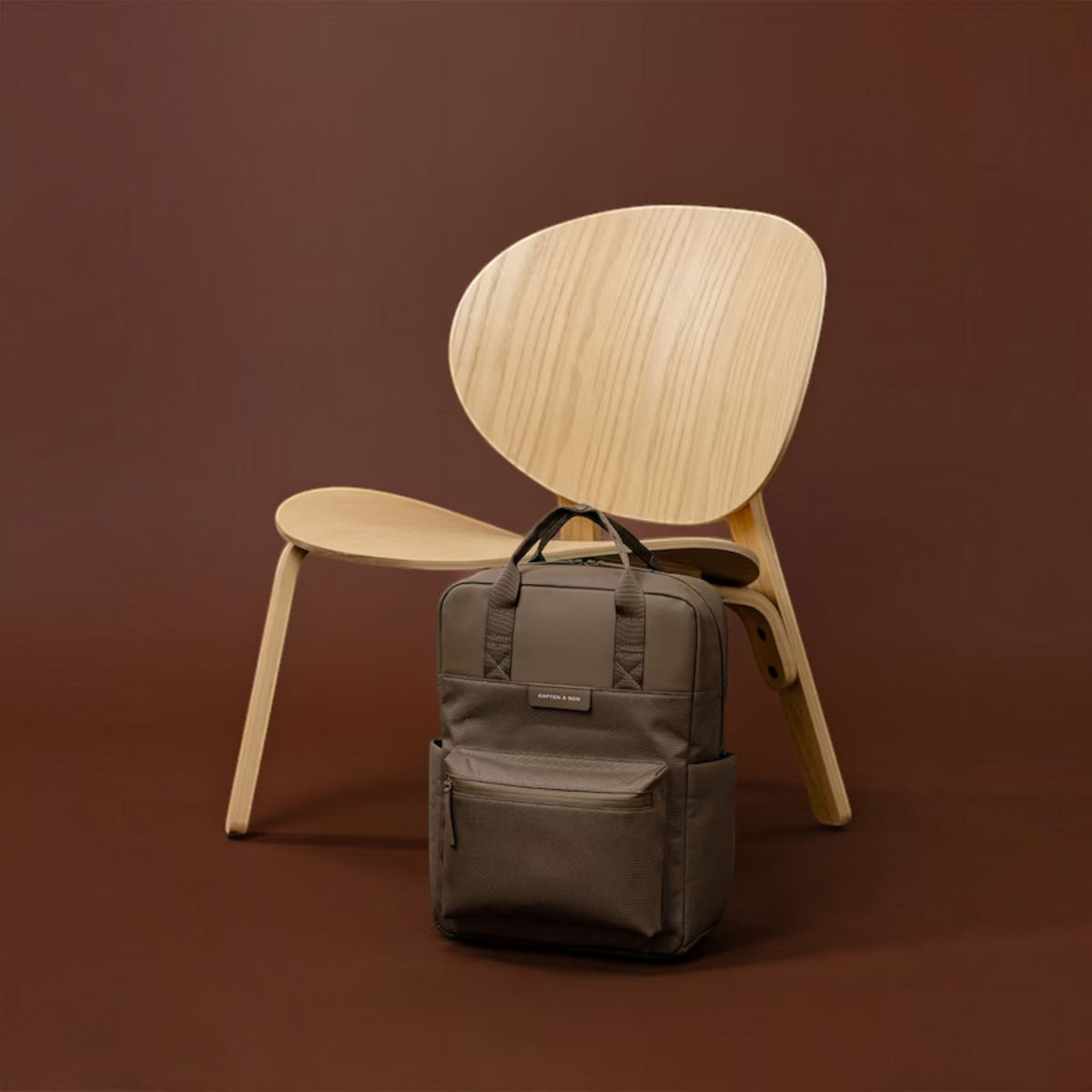 Lieblingstasche Bergen Pro backpack in taupe with padded straps and laptop compartment against a wooden chair