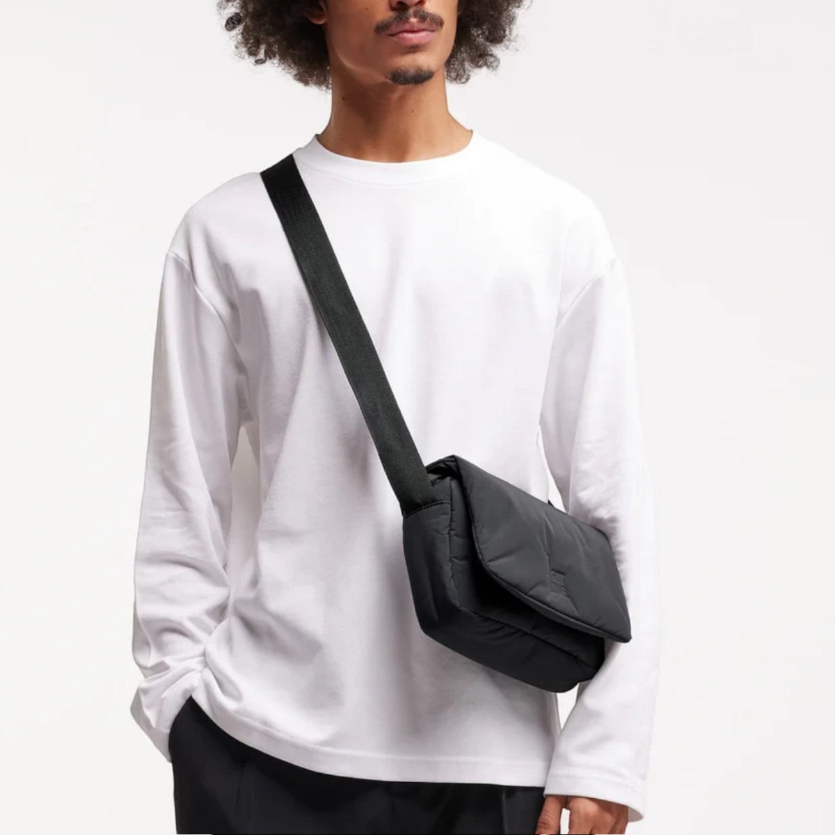 Lieblingstasche Cloud Crossbody Bag in black, made from water-resistant RE:NYNET material, worn by a male model.