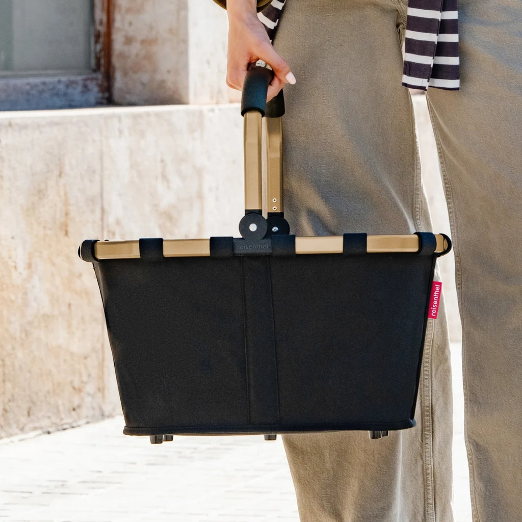 Lieblingstasche black carrybag shopping basket with a sturdy gold-tone aluminium handle held by a person outdoors