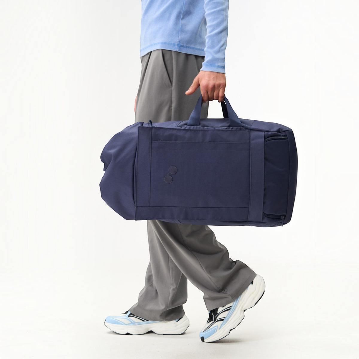 Lieblingstasche Blok Large navy blue duffel bag held by a person wearing grey trousers and light blue top