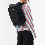 Lieblingstasche Day Pack FLX black backpack worn by a smiling woman in a striped long-sleeve shirt