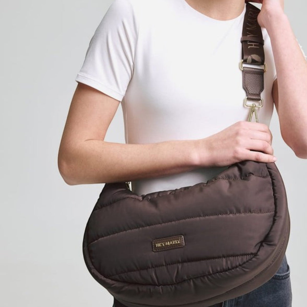 Lieblingstasche Lifetime Buddy M brown quilted crescent shoulder bag with branded strap worn by a smiling woman