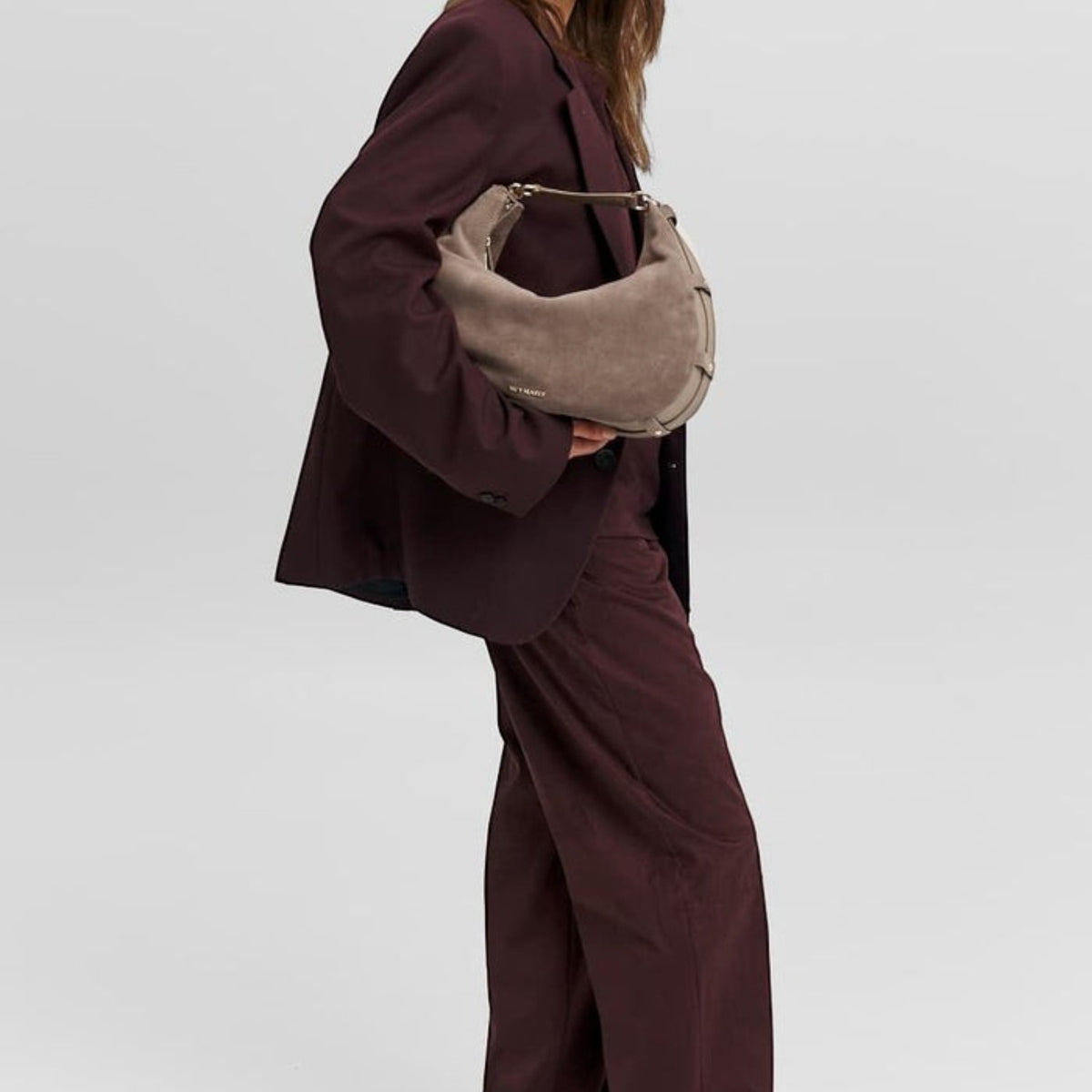 Lieblingstasche Lifetime Sister Suede M taupe suede hobo bag carried by a woman in a dark burgundy suit