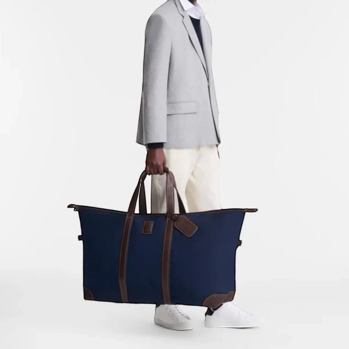 Lieblingstasche Longchamp Boxford navy blue canvas travel bag with brown leather trim held by a man in a grey blazer