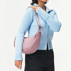 Lieblingstasche mauve sling bag worn crossbody by a model in a light blue ribbed zip-up sweater