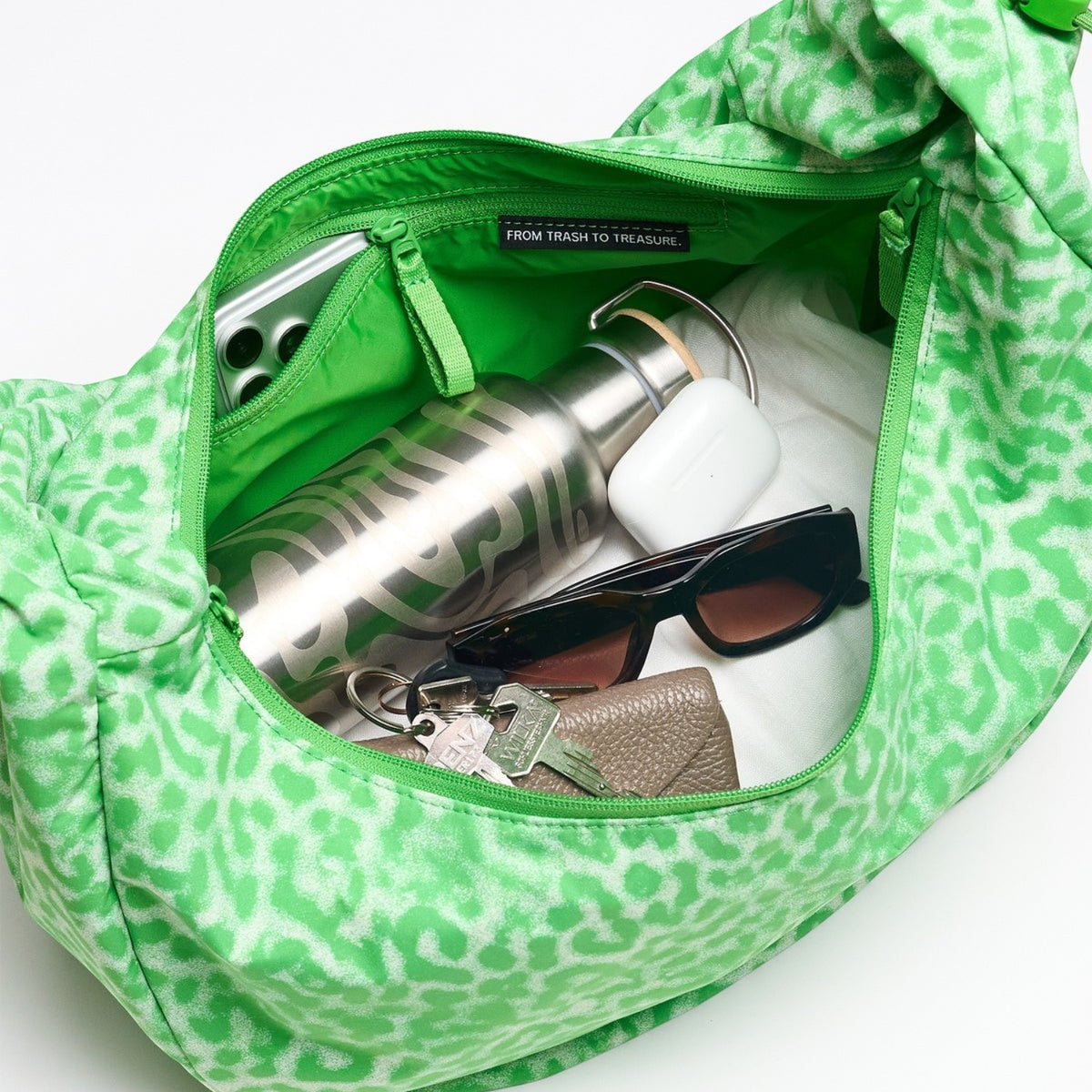 Lieblingstasche Moon Bag Ruffle Large in green animal print, showing interior with water bottle, keys, and accessories.