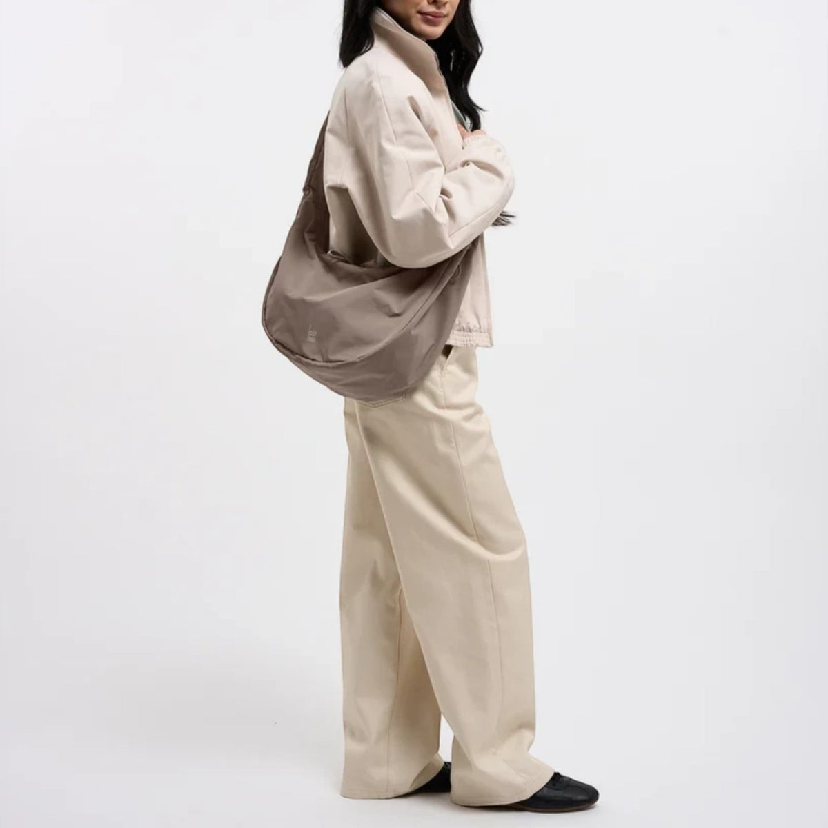 Lieblingstasche Moon Bag Ruffle Large in taupe, worn as a crossbody bag by a woman in beige clothing.