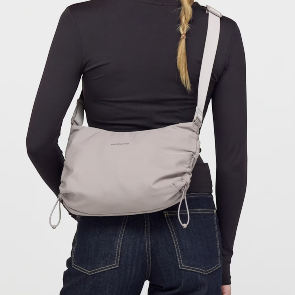 Lieblingstasche Skara Small grey crossbody bag worn by a woman in a black long-sleeve top and dark blue jeans